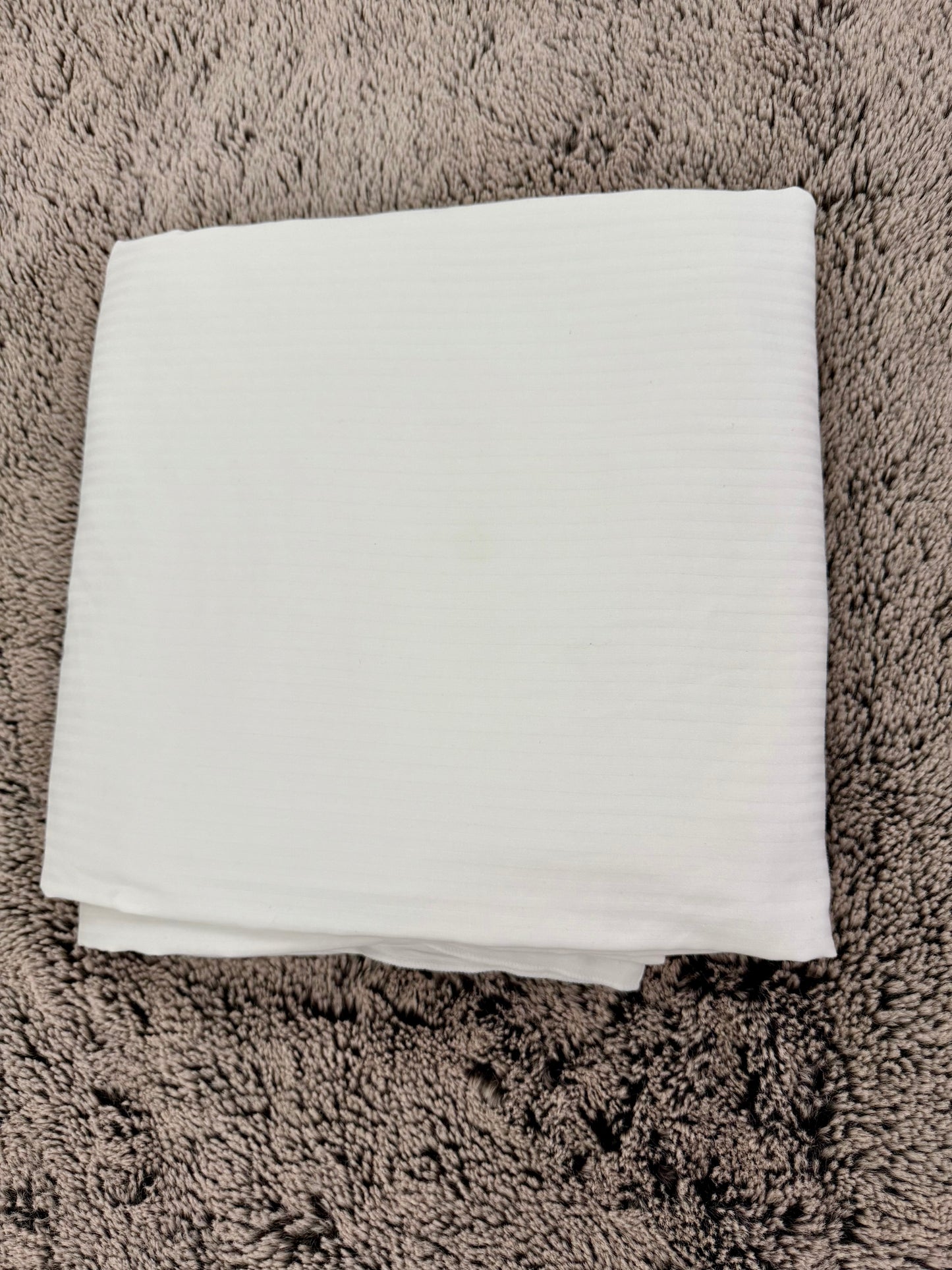 Housse de couette blanche en linge hôtelier recyclé, pliée avec soin, idéale pour chambres Airbnb, gîtes et maisons d’hôtes.