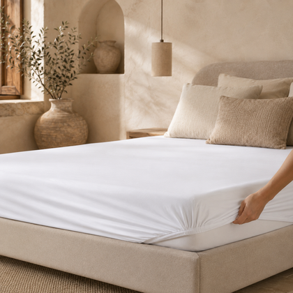 Drap-housse blanc en cours d’installation sur un matelas, montrant son bord élastique et son maintien autour de l’angle du lit.