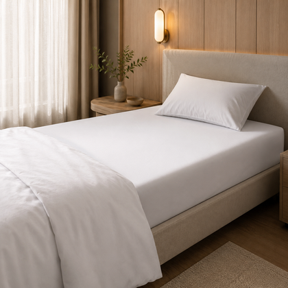 Drap-housse blanc installe sur un matelas dans une chambre chaleureuse au style hotelier, avec une finition nette et soignee.