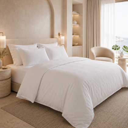 Housse de couette blanche 220x240 cm installée sur un grand lit dans une chambre lumineuse avec vue extérieure, ambiance hôtelière haut de gamme.