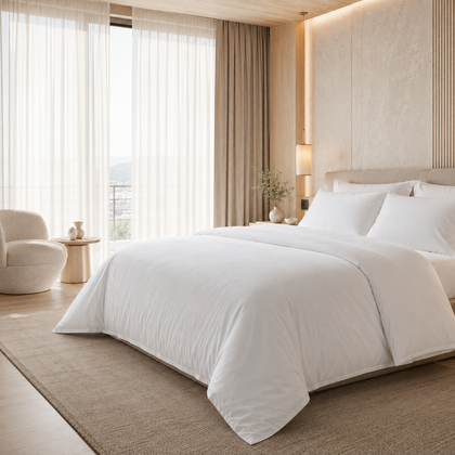 Housse de couette hôtelière blanche 220x240 cm présentée sur un lit double dans une chambre élégante aux tons beige et ivoire.