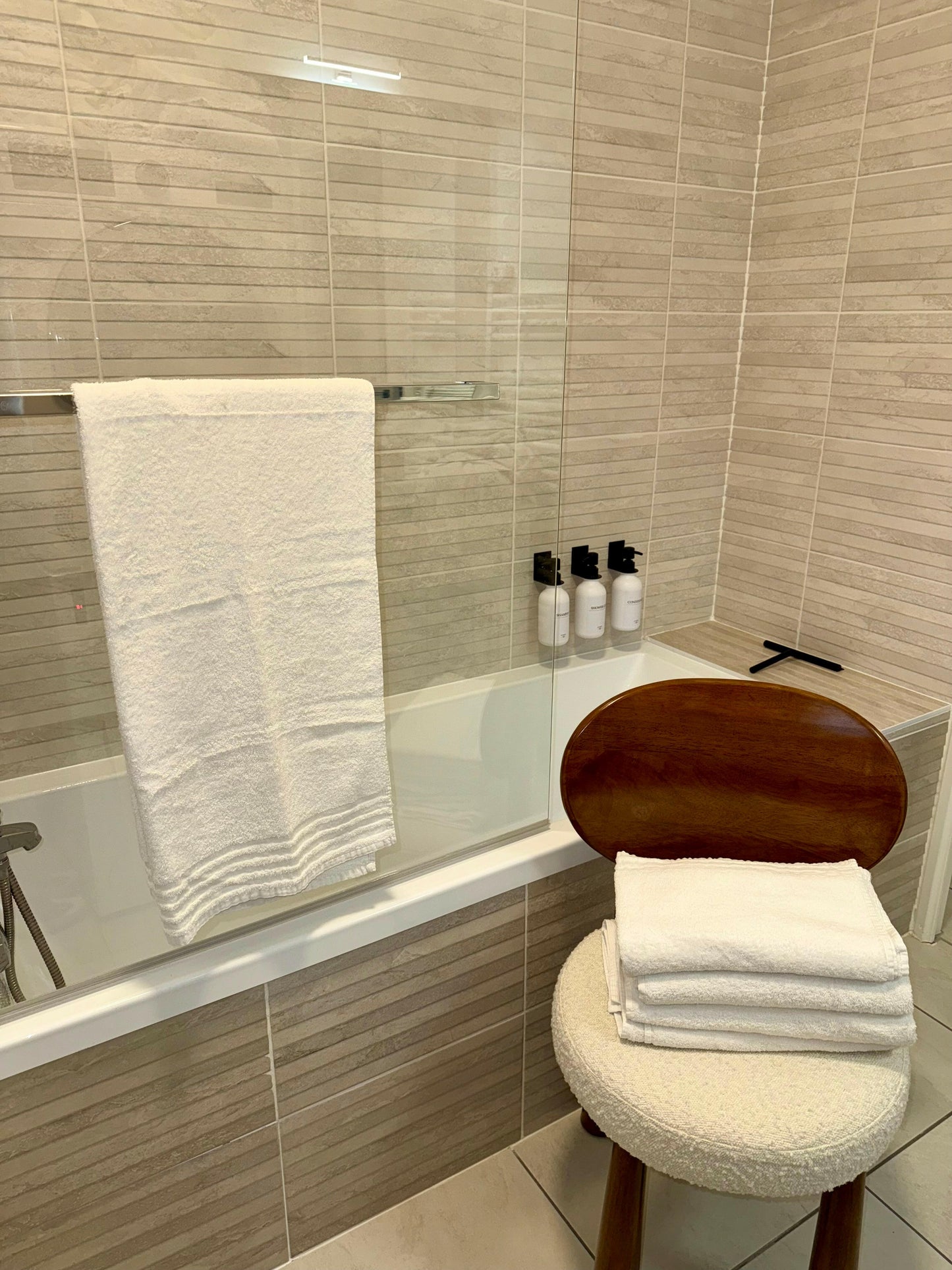 Salle de bain moderne avec serviette de bain recyclée de 70x140 cm, Eco Wayve, accrochée et pliée sur une chaise, parfait pour une ambiance élégante et écologique.