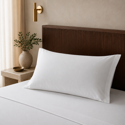 Taie d oreiller hoteliere blanche 50x75 cm installee sur un lit avec une autre taie pliee au premier plan, dans une ambiance lumineuse et raffinee.