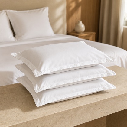 Trois taies d’oreiller blanches 65x65 cm en polycoton empilées dans une chambre d’hôtel